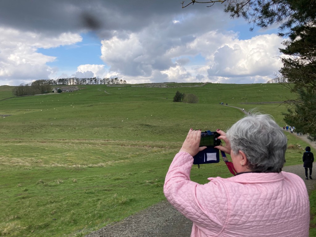 Julie taking a picture of me taking a picture of the Housesteads fort. The white dots are sheep.